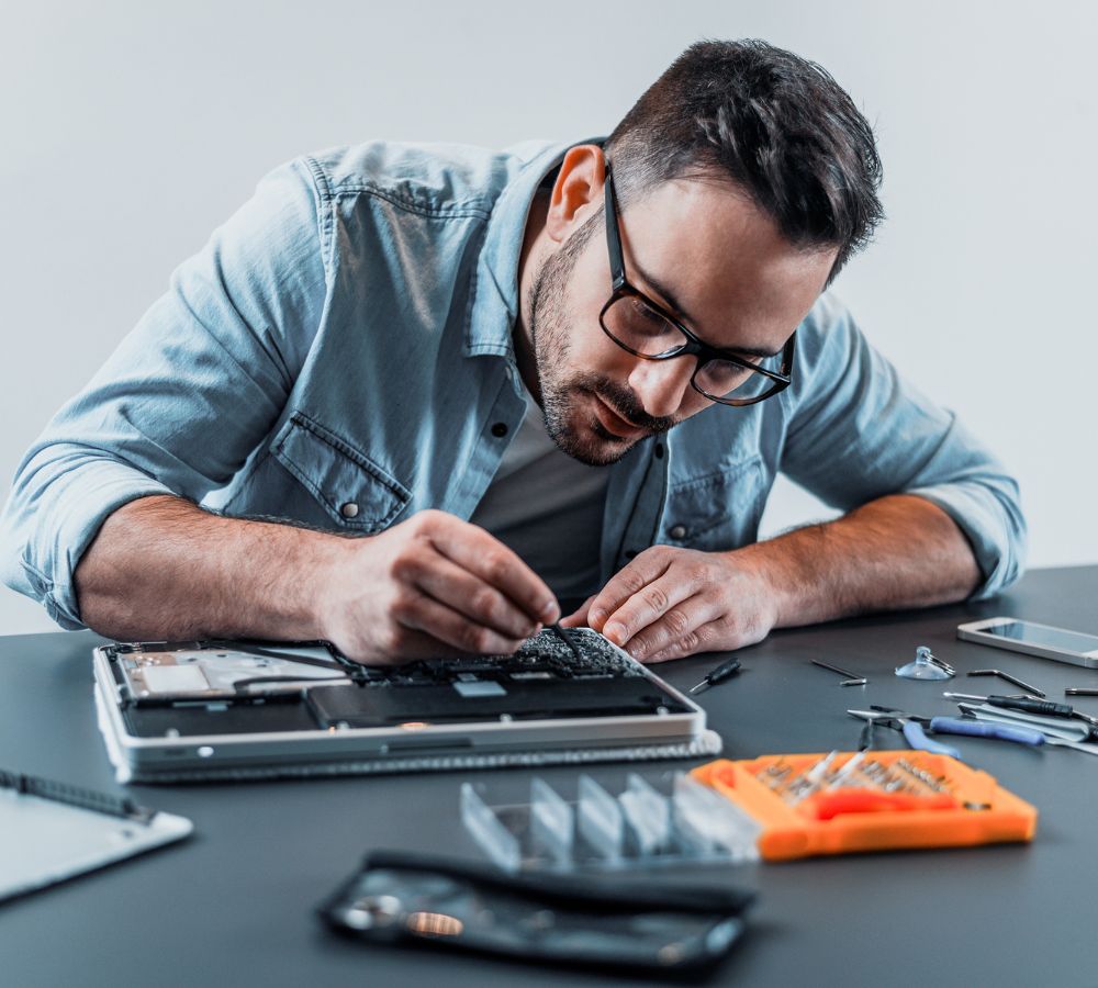 Handsome engineer repairing laptop computer.